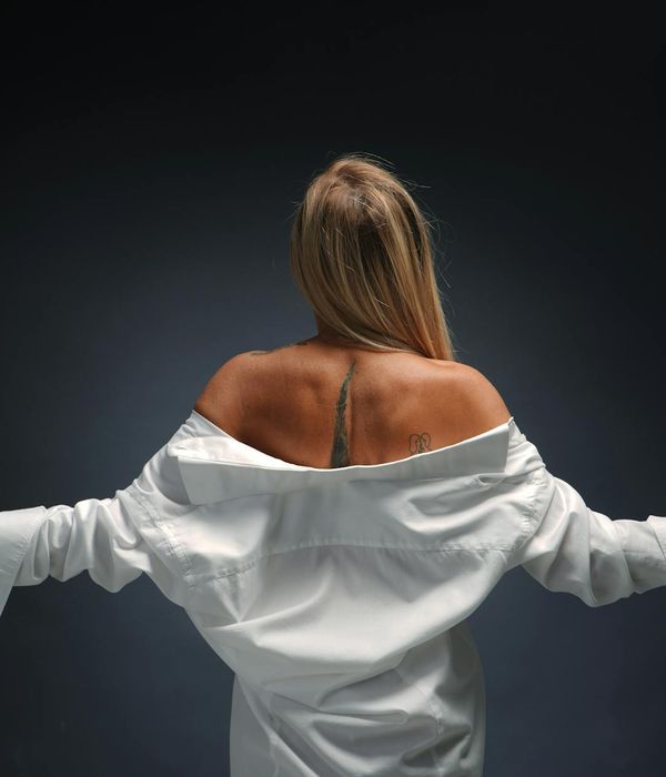 Woman in a peaceful yoga pose against a dark background with cyan light.
